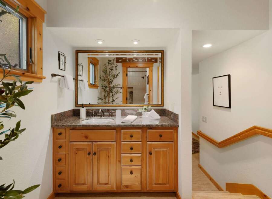 This stunning bathroom features a beautiful wooden vanity with ample storage and a granite countertop, offering both style and functionality.