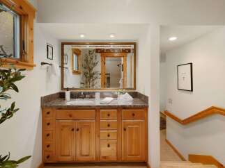 This stunning bathroom features a beautiful wooden vanity with ample storage and a granite countertop, offering both style and functionality.