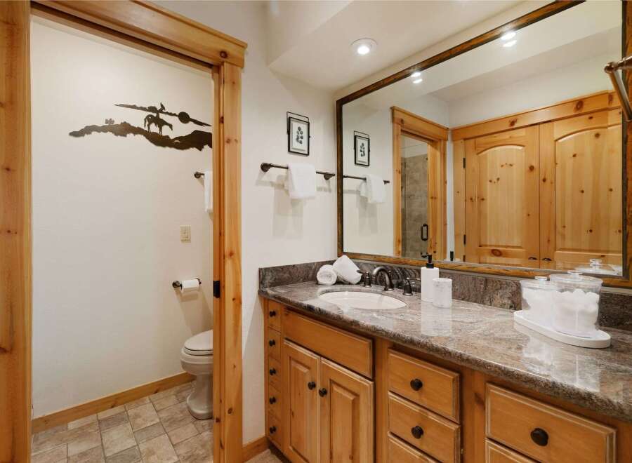 This stunning bathroom boasts a rustic charm with its wooden cabinetry and trim, creating a warm and inviting atmosphere.