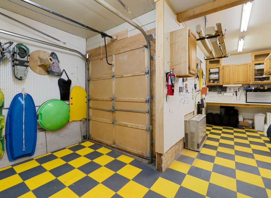 This garage boasts a unique yellow and gray checkered floor, offering a stylish and functional space.