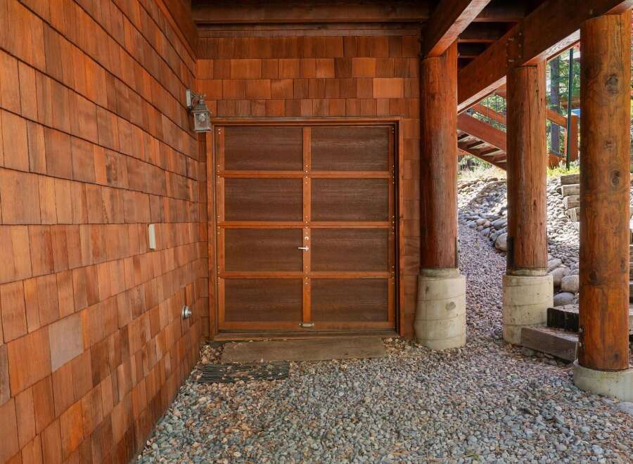 This stunning property boasts a beautiful wooden garage door, complemented by the warmth of cedar shake siding.