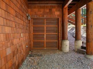 This stunning property boasts a beautiful wooden garage door, complemented by the warmth of cedar shake siding.