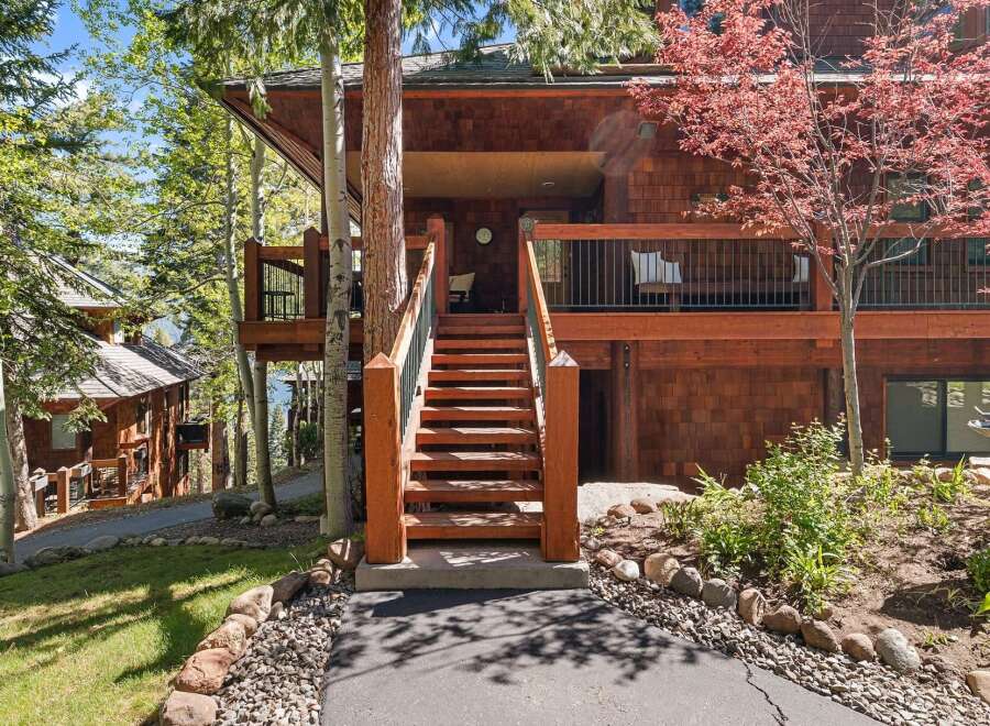 Nestled in a serene, wooded setting, this stunning property boasts a charming wooden exterior and inviting staircase.