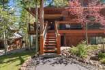 Nestled in a serene, wooded setting, this stunning property boasts a charming wooden exterior and inviting staircase.