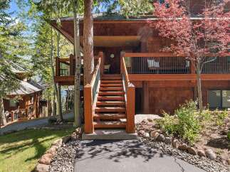 Nestled in a serene, wooded setting, this stunning property boasts a charming wooden exterior and inviting staircase.