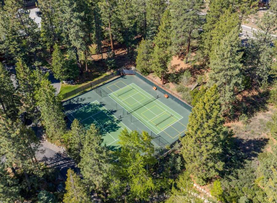 Nestled amidst a lush forest, this property boasts a private tennis court, perfect for active living and outdoor recreation.