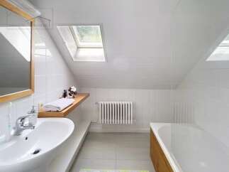 Discover this charming bathroom with a unique sloped ceiling and a skylight that floods the space with natural light.