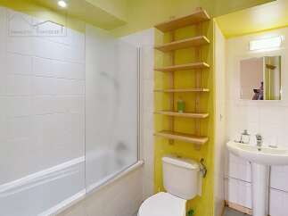 Discover this charming bathroom featuring a bright yellow accent wall and practical wooden shelving.
