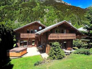 Escape to the mountains in this stunning chalet! This property features a beautiful wooden exterior, a hot tub, and a spacious deck perfect for entertaining.