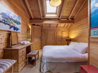 This charming bedroom features a warm, inviting ambiance with its wooden paneling and natural light from the skylight.