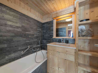 This stunning bathroom features a modern design with natural wood elements and a sleek stone wall.