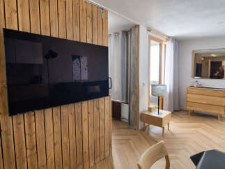 Discover modern living in this stylish property, featuring a sleek, wall-mounted TV and a unique wooden accent wall.