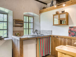 This charming kitchen boasts a rustic aesthetic with its wooden cabinetry and exposed beams, creating a warm and inviting atmosphere.
