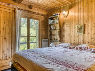 Cozy bedroom with wooden walls and ceiling, offering a warm and inviting atmosphere.
