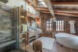 Experience luxury in this stunning bathroom featuring a rustic wooden design and a modern freestanding bathtub.