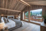 Experience luxury living in this stunning bedroom featuring a cozy fireplace and a breathtaking view.