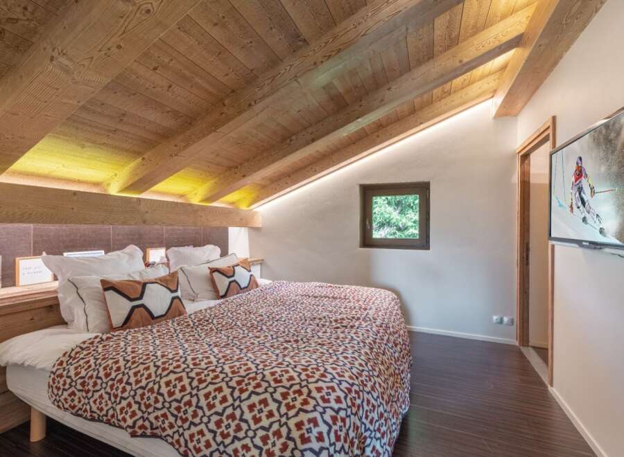 Experience the charm of this cozy bedroom featuring a unique sloped ceiling with exposed wooden beams.