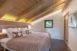 Experience the charm of this cozy bedroom featuring a unique sloped ceiling with exposed wooden beams.
