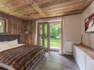 Experience rustic charm in this cozy bedroom, featuring a warm wooden ceiling and walls.