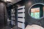 This luxurious bathroom boasts a sleek, modern design with striking black marble walls and a spacious walk-in shower.