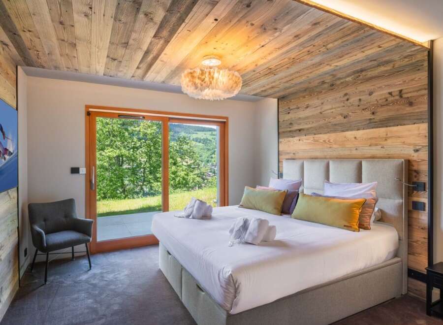 Experience luxury in this stunning bedroom featuring a rustic wooden ceiling and accent wall.