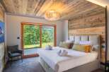 Experience luxury in this stunning bedroom featuring a rustic wooden ceiling and accent wall.