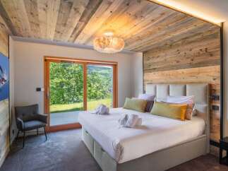 Experience luxury in this stunning bedroom featuring a rustic wooden ceiling and accent wall.