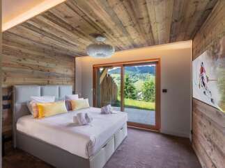 Experience luxury living in this stunning bedroom featuring a cozy wooden ceiling and walls.