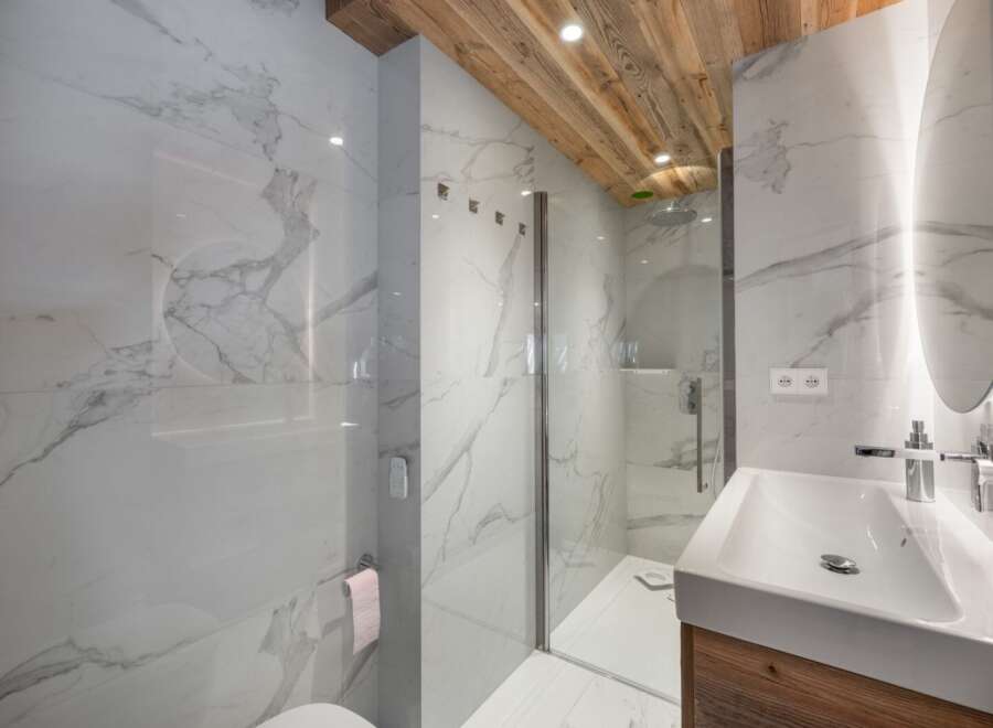 This luxurious bathroom features stunning marble walls and a wooden ceiling, creating a spa-like atmosphere.