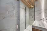 This luxurious bathroom features stunning marble walls and a wooden ceiling, creating a spa-like atmosphere.