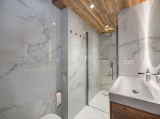 This luxurious bathroom features stunning marble walls and a wooden ceiling, creating a spa-like atmosphere.