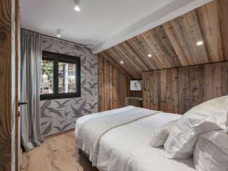 This cozy bedroom features a rustic wooden ceiling and walls, creating a warm and inviting atmosphere.
