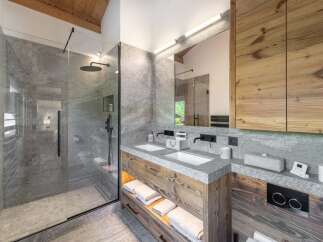 Experience luxury in this stunning bathroom featuring a modern glass shower, sleek black fixtures, and a double vanity.