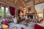 Experience the warmth of this stunning chalet-style living room, featuring a cozy fireplace and exposed wooden beams.