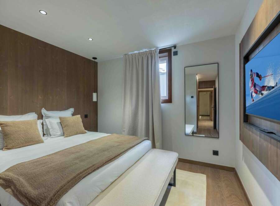 Experience luxury in this stunning bedroom featuring a cozy bed, plush pillows, and a warm, inviting color palette.