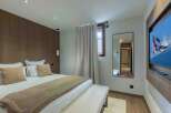 Experience luxury in this stunning bedroom featuring a cozy bed, plush pillows, and a warm, inviting color palette.