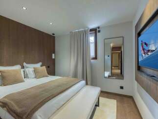Experience luxury in this stunning bedroom featuring a cozy bed, plush pillows, and a warm, inviting color palette.