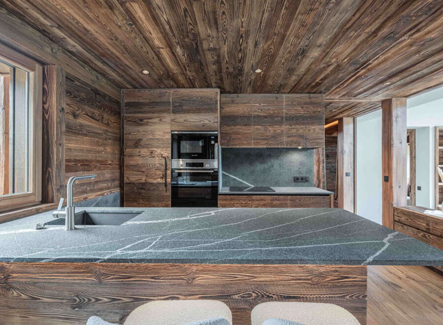 Experience rustic elegance in this stunning kitchen, featuring rich wood paneling and a sleek, modern countertop.