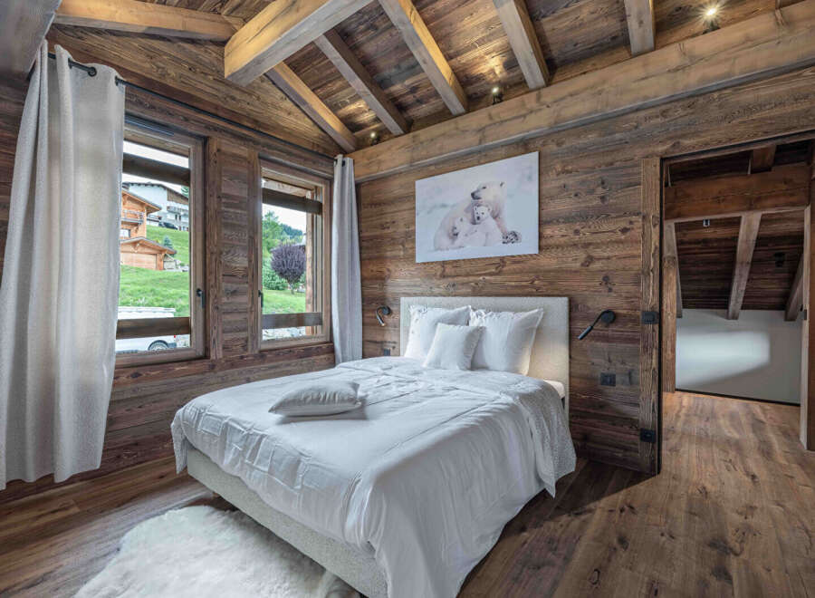 This stunning bedroom boasts a rustic charm with its wooden walls and ceiling, creating a warm and inviting atmosphere.