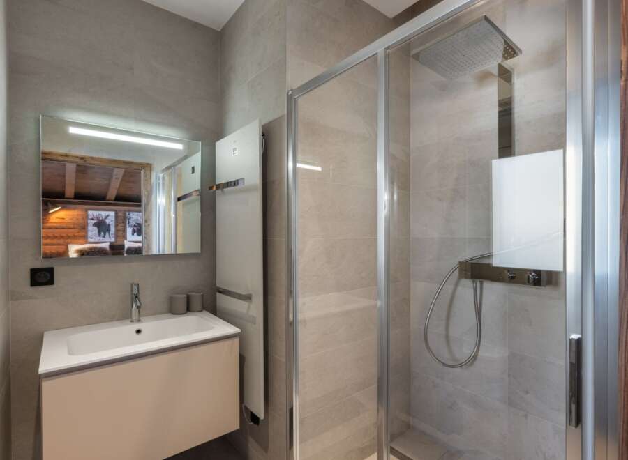This modern bathroom boasts a sleek design with a spacious shower and a stylish vanity.