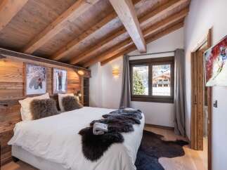 This cozy bedroom features a rustic wooden ceiling and walls, creating a warm and inviting atmosphere.