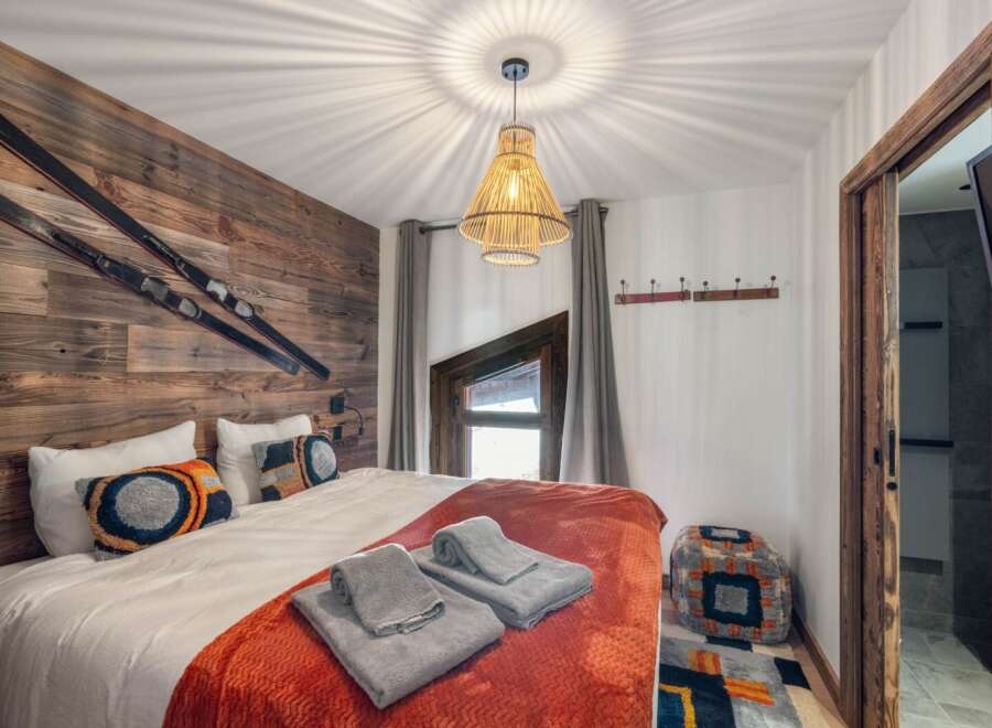 This cozy bedroom features a rustic wooden accent wall adorned with skis, creating a unique alpine ambiance.