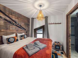This cozy bedroom features a rustic wooden accent wall adorned with skis, creating a unique alpine ambiance.