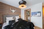 Experience luxury in this stunning bedroom featuring a unique wood-paneled wall and a stylish headboard.
