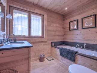 This stunning bathroom boasts a warm, inviting ambiance with its natural wood paneling and flooring.