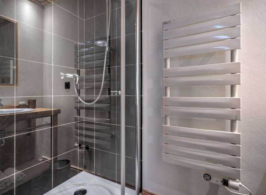 Step into a modern bathroom with a sleek shower enclosure and stylish heated towel rack.
