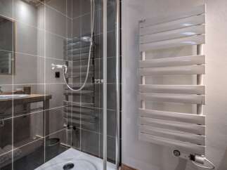 Step into a modern bathroom with a sleek shower enclosure and stylish heated towel rack.