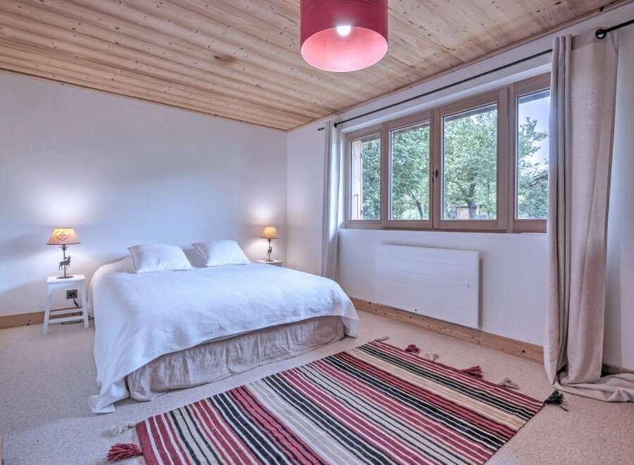 This charming bedroom features a cozy atmosphere with a wooden ceiling and a comfortable bed.
