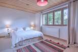 This charming bedroom features a cozy atmosphere with a wooden ceiling and a comfortable bed.
