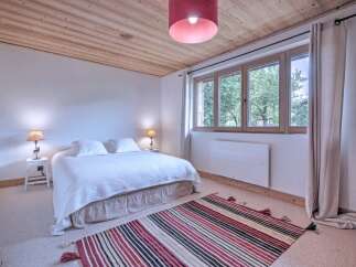 This charming bedroom features a cozy atmosphere with a wooden ceiling and a comfortable bed.